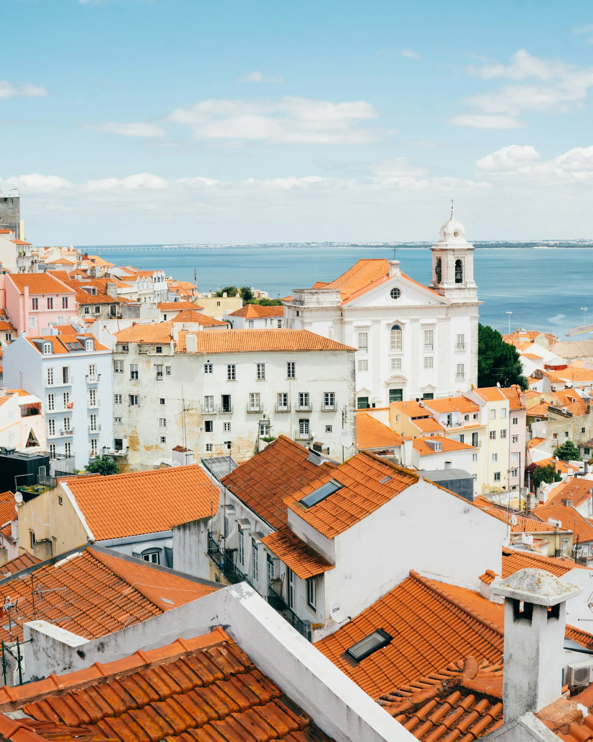 White houses and terracotta roofs running down to the river in Lisbon